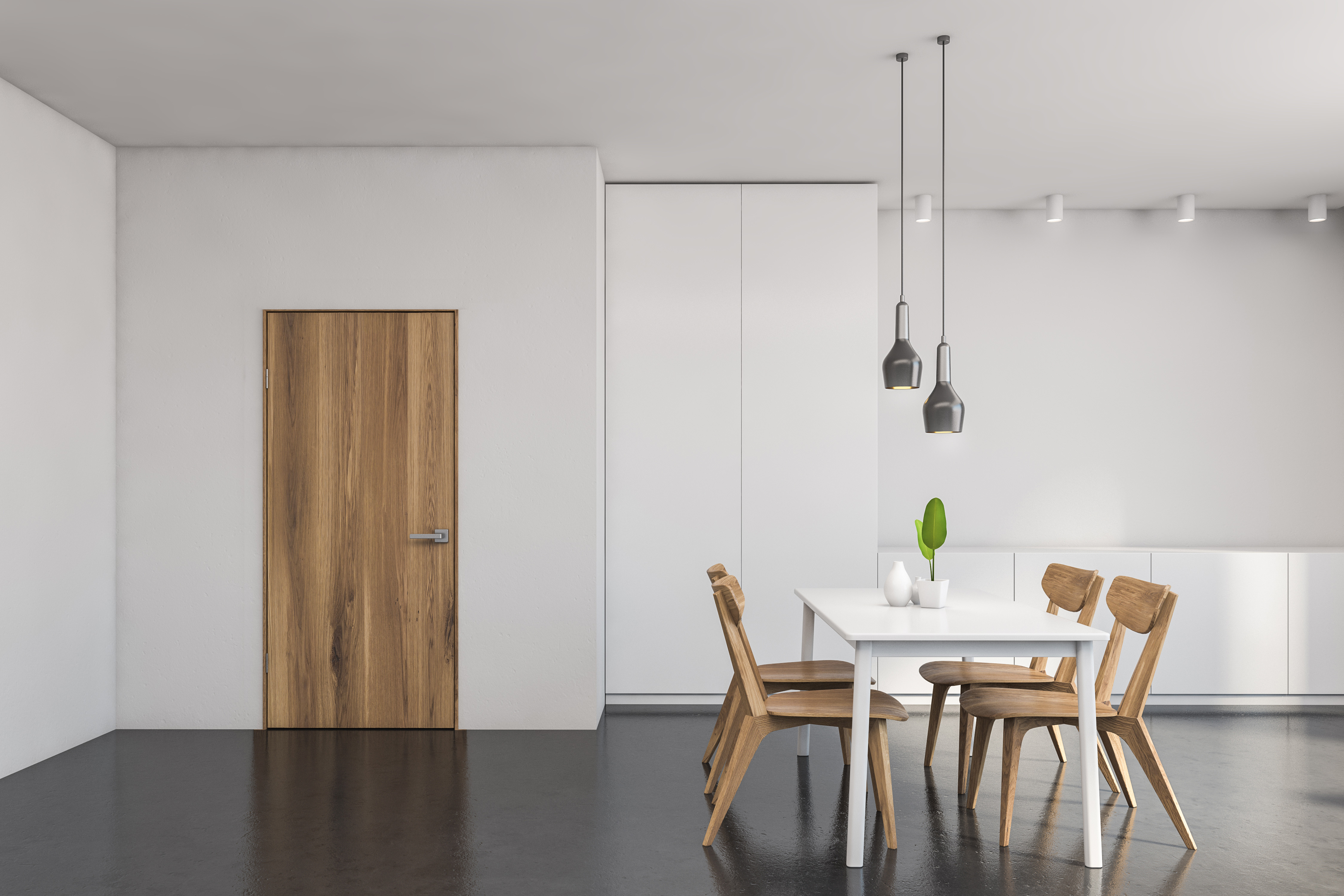 A modern dining area featuring a wooden door, a white dining table surrounded by wooden chairs, and pendant lighting. A small plant decorates the table, with white cabinets visible in the background.